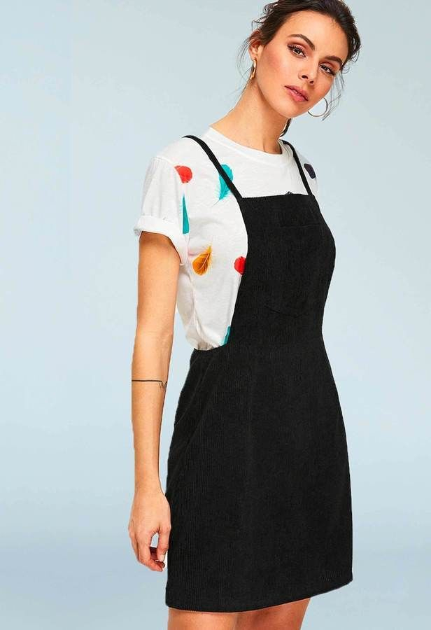 woman in a white tshirt and a black pinafore / overalls dress, side view