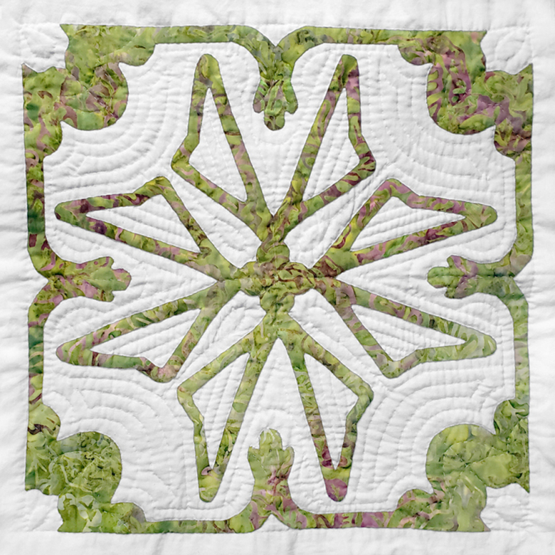 Applique quilt block with light green harps and a scalloped border on a white background