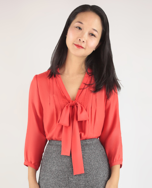 From pattern website. Woman wearing a blouse with pin tucks and a bow on the front and three-quarter sleeves