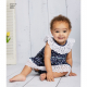 A toddler sitting wearing a blue ruffled dress