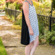 Side view of entire dress in black and black-and-white fabric against a background of sidewalk and greenery.