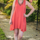 Front view of entire dress in dark pink fabric against a background of sidewalk and greenery.