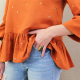 Close up view of front side hemline and sleeve ruffle of blouse