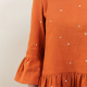 Close up front view of sleeve and hem ruffle detail of blouse