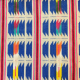 fabric swatch of handwoven ikat, mostly blue and cream and red, with multicolored highlight areas
