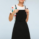 woman in a white tshirt and a black pinafore / overalls dress, front view, with hands on straps