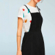 woman in a white tshirt and a black pinafore / overalls dress, side view