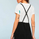 woman in a white tshirt and a black pinafore / overalls dress, back view showing crisscrossing straps
