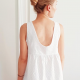 Back view of a woman wearing a white sleeveless top with lace edge detail at the hem.