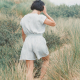 A person wearing a striped, blue and white playsuit standing with their back to the camera