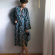 A person wearing a patterned robe and holding a pair of quilted slippers