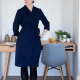 A woman in a navy blue wrap dress with three-quarter sleeves standing in front of a desk against a white wall.