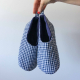 A hand holding up a pair of quilted slippers