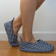 A pair of feet with blue chequered, open top skimmer style quilted slippers