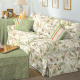 Couch covered in floral pattern with ottoman covered in green fabric
