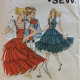 vintage pattern cover, showing 2 ladies spinning in tiered pinafores, in front of a white man in a western shirt