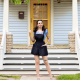 Woman standing in front of front stoop of house with a denim short overall outfit