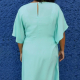 Woman's back in a seafoam dress standing against a blue wall