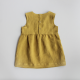 Back view of a yellow baby dress laid flat on a grey background. The dress has a plain, sleeveless bodice with snaps closing the centre back and a gathered skirt.