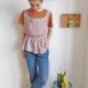 Image of a woman with short brown hair wearing a sleveeless top in a flowery lilac double gauze fabric