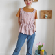 Image of a woman with short brown hair wearing a sleveeless top in a flowery lilac double gauze fabric. She is also wearing jeans and looking at the camera