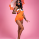 A black woman wearing sunglasses and holding an orange and white parasol, wearing an orange a white swimsuit standing against a pink background.