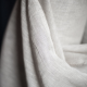 sheer off white fabric in a roll against a black background