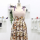 Front-view photo of Oleander, a sleeveless dress with purple ribbons tied into bows for shoulder straps, pale pink sweetheart neckline bodice, and floral-print box pleated skirt with a wide waistband that starts at the underbust, on a dress form.
