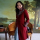 Photo of Sewstine wearing her Kefta coat, a red wool coat with a high collar and silver embroidery around the neckline and sleeve cuffs.