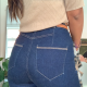 back view of a slim woman who wears tight dark blue jeans and a beige top