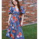 A young woman wearing a wrap dress made from a floral print light blue denim fabric.