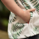 A child's hand in the pocket of a white and green hoodie.