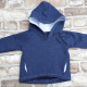 A blue hoodie with white lining laying flat on a grey brick surface.