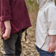Two children standing facing each other. The taller child is wearing a wine coloured hoodie and the shorter child is wearing a white hoodie. The photo is cropped to show the children only from shoulder to knee,